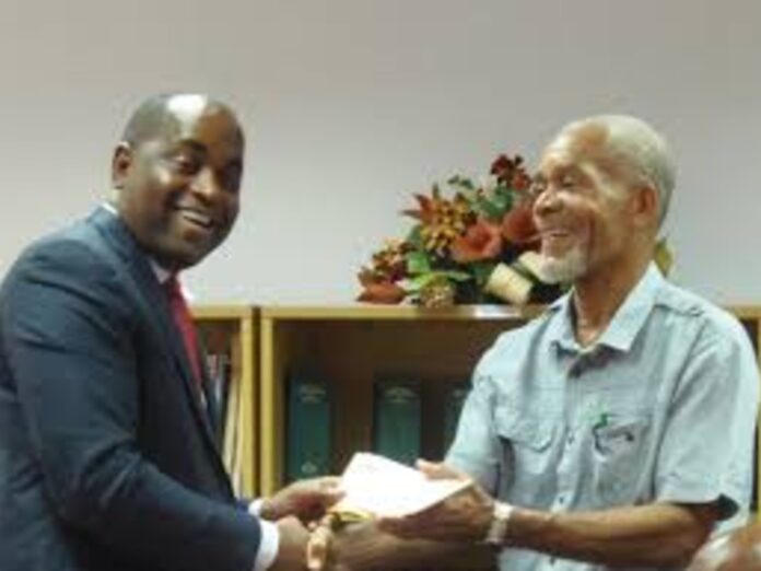 Luke Prevost receiving cheque from PM Skerrit