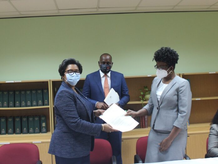 Manager of AID Bank Marie-Therese Johnson and FC Edwards exchange documents after the signing
