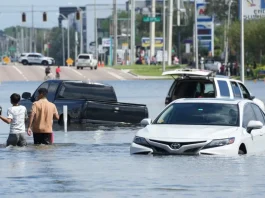 Children walk past vehicles flooded in the water as the streets of the Southeast Seminole Heights section of Tampa due to Hurricane Milton on October 10, 2024 in Florida.