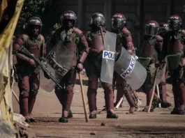 (FILES) Kenyan Police officers watch protesters as they block the street during a mass rally called by the opposition leader Raila Odinga who claims the last Kenyan presidential election was stolen from him and blames the government for the hike of living costs in Kibera, Nairobi on March 27, 2023. A Kenyan force will leave for Haiti on June 25 to lead a UN-backed multinational mission to tackle gang violence in the Caribbean country, government and police sources said on June 23, 2024. (Photo by YASUYOSHI CHIBA / AFP)